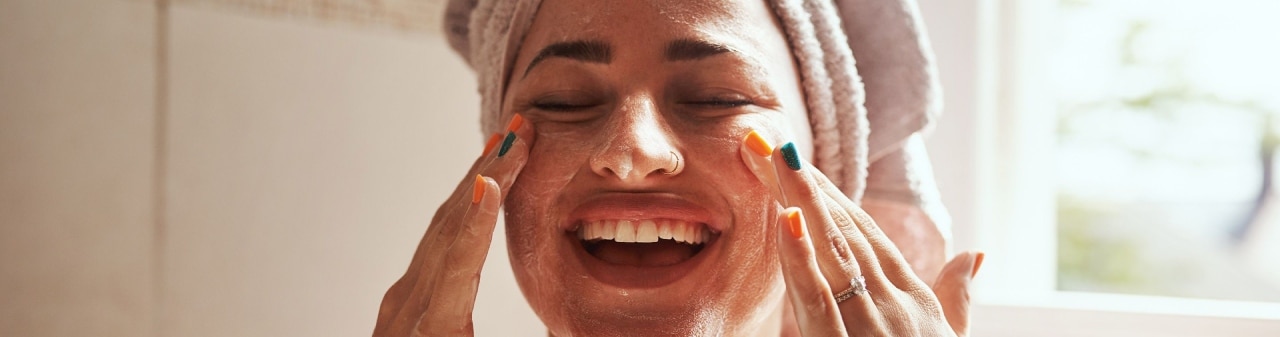 mujer dándose un masaje facial en casa
